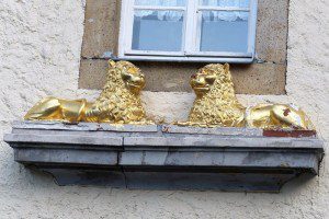 Lvi s tváří dobromyslných opic na římse portálu "Panského domu" ve Schmalzgrube